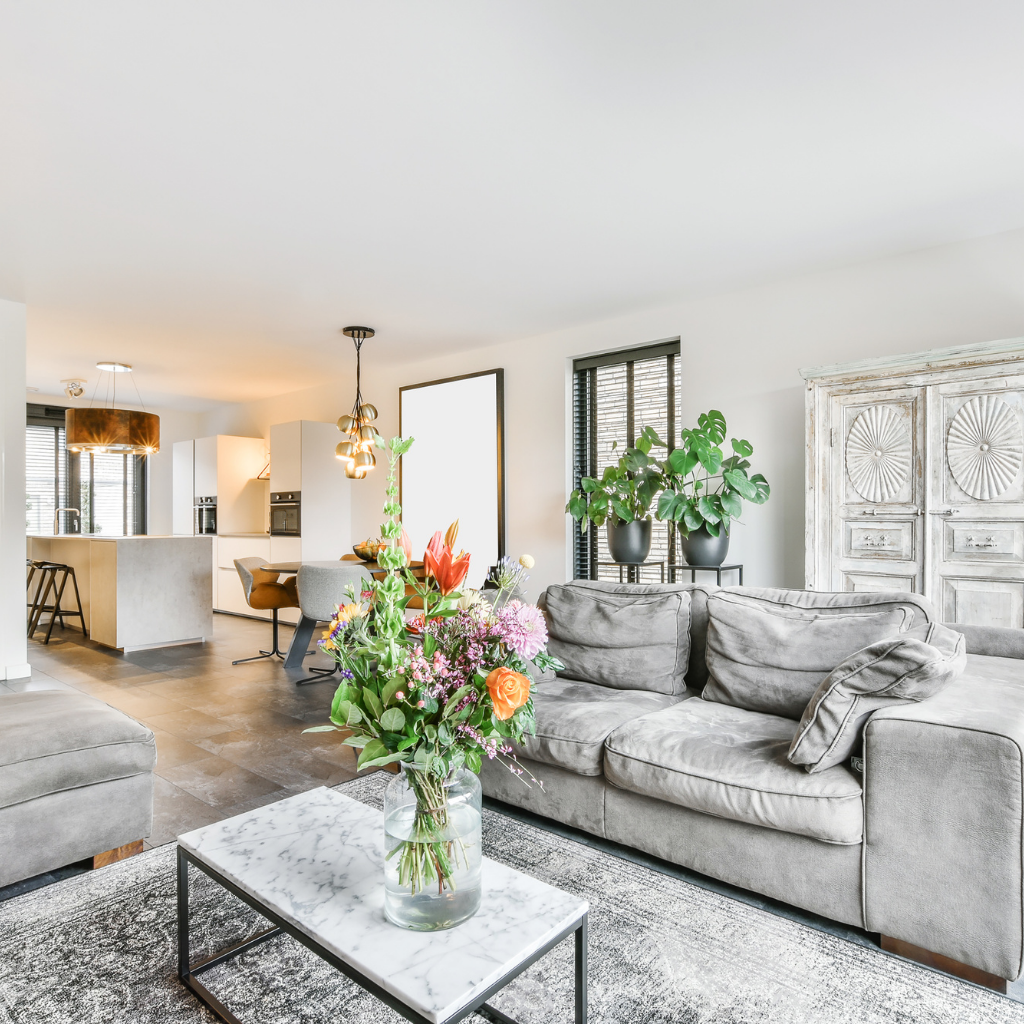Professional results of Affordable House Cleaning in Buda, Texas, showing a clean, bright, and tidy modern living room with flowers and an open-concept kitchen area.