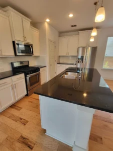 Polished black granite kitchen island and stainless steel appliances in a spotless home, showcasing our detailed move out cleaning Austin service.