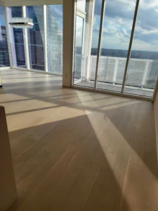 Spacious empty living room with hardwood floors mopped and sun-lit windows cleaned for a luxury Move In Cleaning Austin client.
